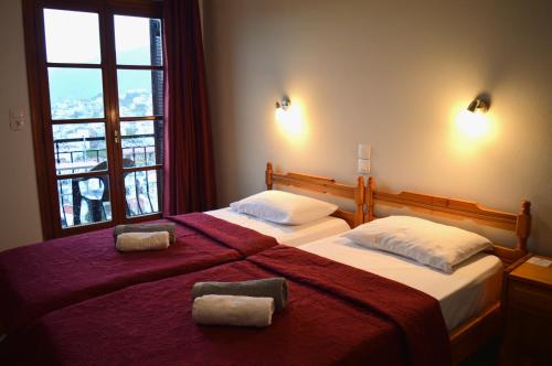 斯基亚索斯镇Pension Mando的一间卧室设有两张带红色床单的床和窗户。