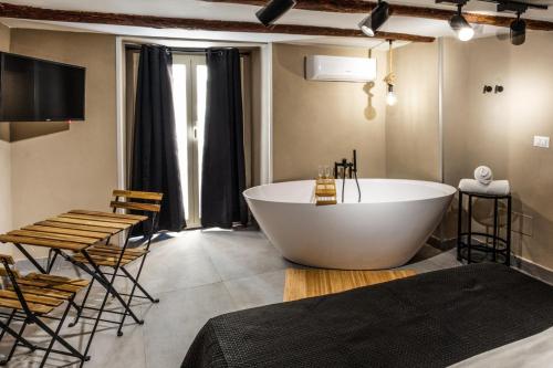 那不勒斯Pendino Luxury Rooms的一间带大浴缸、桌子和椅子的浴室