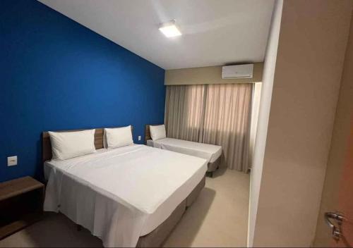 阿瓜斯-迪圣佩德罗São Pedro Thermas Resort Parque的卧室配有一张白色大床和蓝色的墙壁