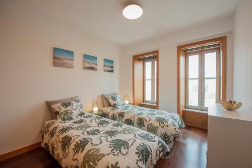 马托西纽什Porto Metro-At-Home Apartment的一间卧室设有两张床和两个窗户。