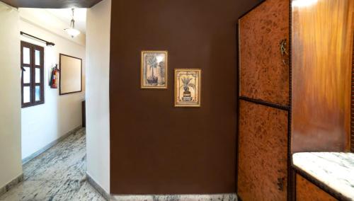加尔各答Aster Guest House的走廊上设有棕色墙壁,上面有图片