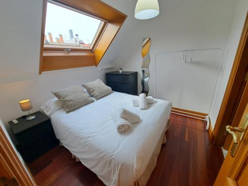 维戈Vigo centro, ático.的一间卧室配有一张带白色床单的床和一扇窗户。