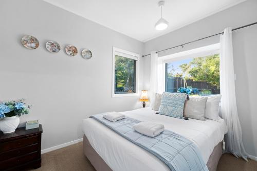陶波Botanical HideAway Taupo的白色的卧室设有床和窗户