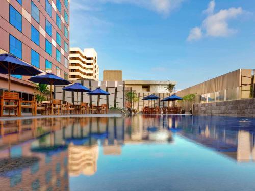 新加坡Grand Mercure Singapore Roxy的一个带蓝伞和桌椅的游泳池