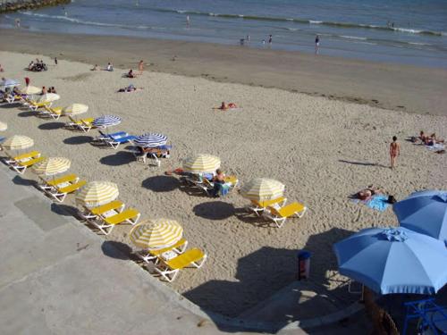 鲁瓦扬Best Western Hôtel Royan Océan的海滩上方的椅子和遮阳伞