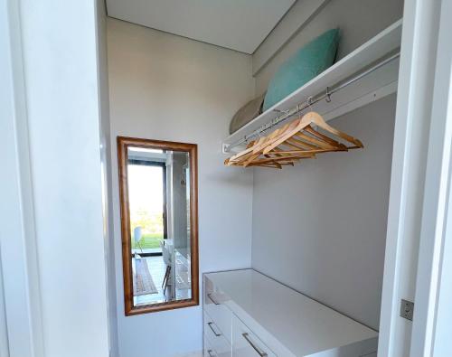 悉尼Manly Paradise Apartment的步入式衣柜,配有白色架子和镜子