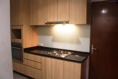 雅加达雅加达西玛图邦城中住宿酒店的厨房配有木制橱柜和炉灶烤箱。