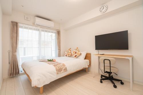 东京リアル大久保　Apartment Hotel的一间卧室配有一张床和一张书桌及电视