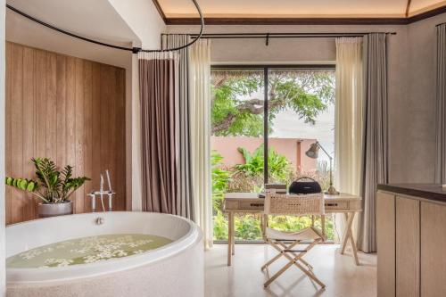 七岩VALA Hua Hin - Nu Chapter Hotels的带浴缸、书桌和窗户的浴室