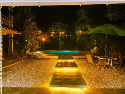 比亚维森西奥Casa hotel Aeroclubr15的夜间游泳池配有桌子和遮阳伞