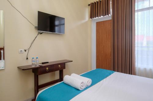 日惹Sans Hotel Kumbang Yogyakarta by RedDoorz的酒店客房,配有床和电视