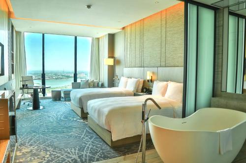 苏州苏州吴江盛虹万丽酒店的酒店客房设有两张床和浴缸。