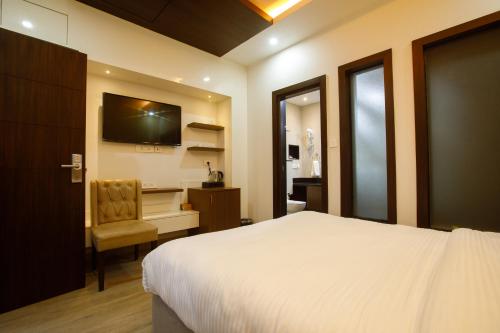 加德满都Sangam City Hotel Pure Veg的一间卧室配有一张床、一把椅子和电视