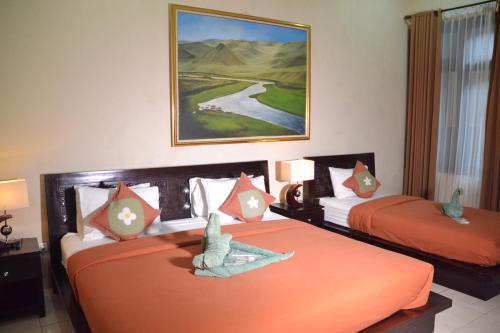 日惹茹玛康婷家庭旅馆的配有橙色床单的酒店客房内的两张床