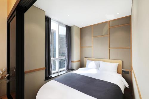 首尔The Stay Classic Hotel Myeongdong的一间卧室设有一张大床和一个窗户。