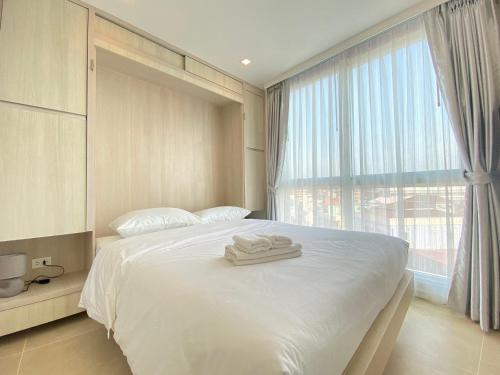 南芭堤雅Olympus city garden的卧室配有白色的床和2条毛巾