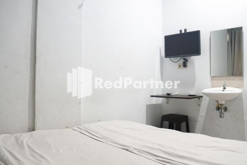 雅加达Cosmo Harmoni RedPartner的一间卧室配有一张床、一个水槽和一台电视