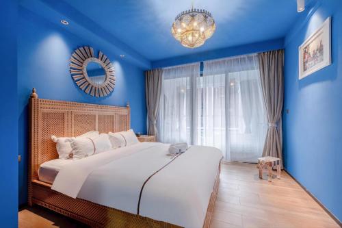 惠东摩洛哥绿屋森林的一间卧室配有一张大床、蓝色的墙壁和吊灯。