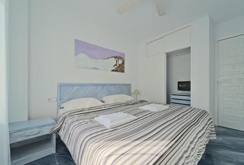 圣安东尼奥伊维萨全套房酒店公寓的白色卧室配有一张带条纹毯子的大床