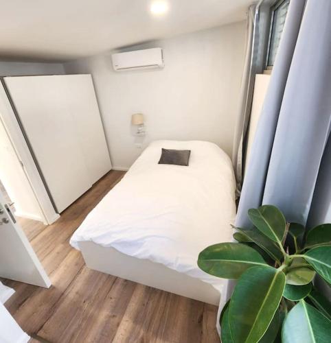 特拉维夫Assuta Residence in Ramat HaHayal, Tel Aviv的一间小卧室,配有白色的床和植物