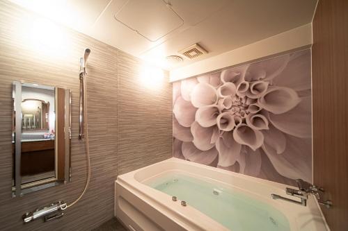 彦根市ホテル リッド 男塾ホテルグループ的浴室设有浴缸,墙上挂有花卉画