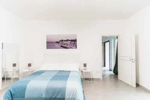 比谢列Le Marine Apartments的白色卧室配有蓝色的床和桌子