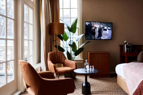 宰斯特科尔克博什城堡酒店的客厅配有沙发、椅子和电视