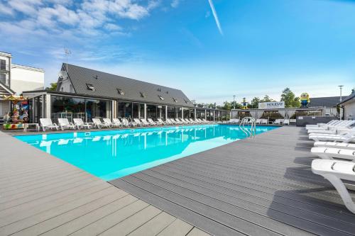 尤斯托尼莫斯基Holiday Park & Resort Ustronie Morskie的一座大型游泳池,旁边设有白色椅子