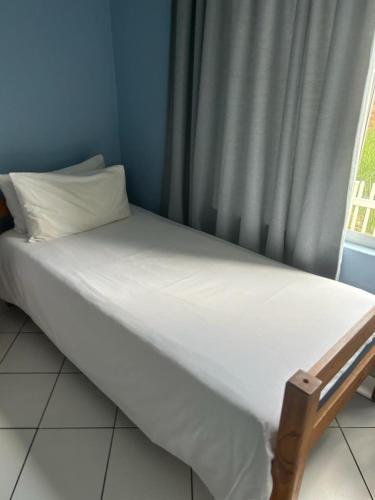 乌旺戈海滩205 Laguna lacrete的一张带白色床单的床和一个带窗帘的窗户