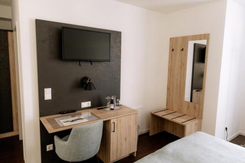 多瑙河畔诺伊堡埃姆夫鲁斯酒店的一间房间,配有一张桌子和一台墙上的电视