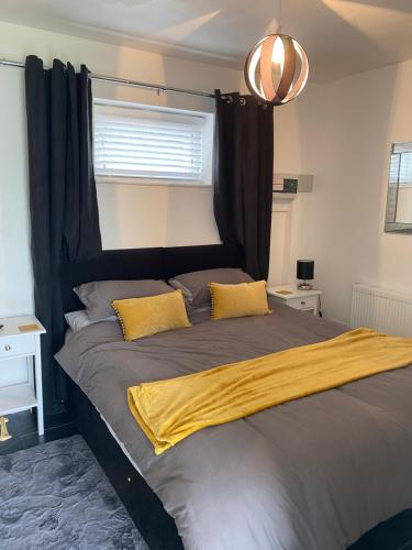 卡迪根Katy’s Cwtch的一间卧室配有一张带黑色床头板和黄色枕头的床。