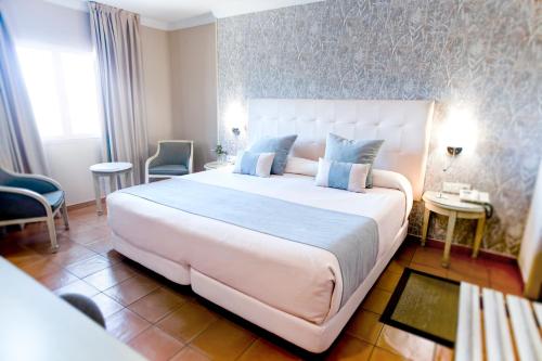 阿尔赫西拉斯阿尔博兰阿尔赫西拉斯酒店的卧室配有带蓝色枕头的大型白色床