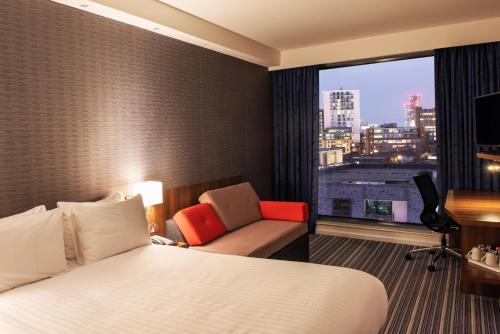 曼彻斯特曼彻斯特城中心体育场智选假日酒店的酒店的客房 - 带一张床、椅子和窗户