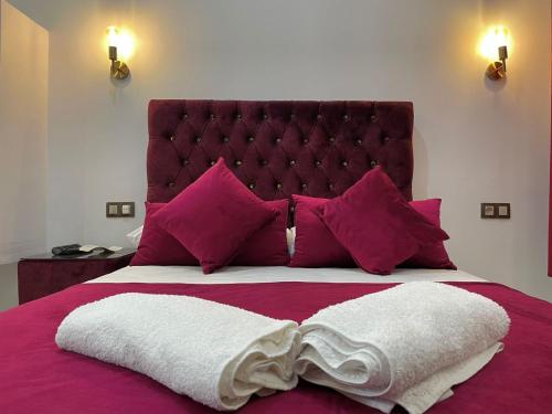 丹吉尔Hotel Palace tanger的一间卧室配有一张大床,提供紫色床单和枕头