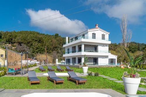 特劳洛斯Mythos Luxury Villa-Skiathos的前面设有躺椅的白色房子