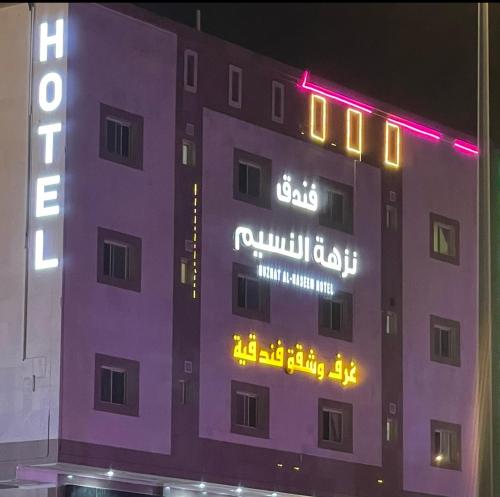 Ash Shishahفندق نزهة النسيم的建筑的侧面有 ⁇ 虹灯标志