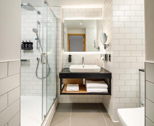 霍尔Holiday Inn Manchester Airport, an IHG Hotel的白色的浴室设有水槽和淋浴。