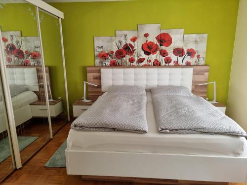 Ferienwohnung Mohnblume的卧室配有白色床,墙上挂着红色鲜花