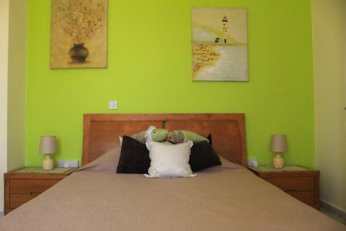 帕福斯Cozy 1 bedroom apartment in walking distance to the municipal beach的一间卧室配有一张带绿色墙壁的床和两盏灯。