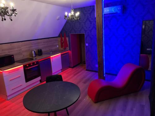 BonnétableLove room avec jacuzzi privé的客厅配有桌椅和紫色照明