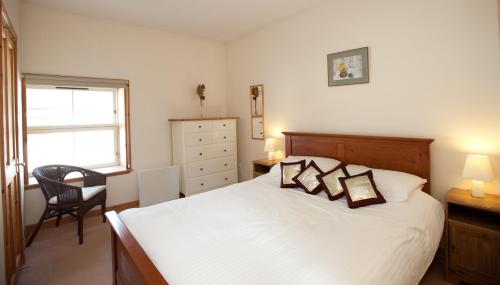 斯特灵The Steading, Back Borland Holiday Cottages的卧室配有床、椅子和窗户。