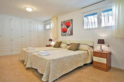 卡尔佩Villa Calalga - PlusHolidays的一间卧室设有两张床和两个窗户。