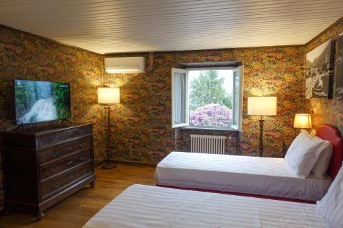 切尔诺比奥CASA VASCONI CERNOBBIO的一间卧室设有两张床、一台电视和一扇窗户。