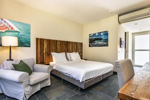 威廉斯塔德Bayside Boutique Hotel - Blue Bay Golf & Beach Resort的一间卧室配有一张床、一张沙发和一把椅子