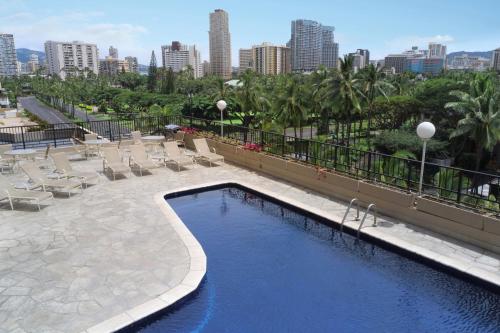 檀香山威基基阿瓜棕榈酒店的一个带躺椅的游泳池,享有城市天际线