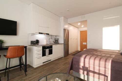 库奥皮奥City Apartment Aapelintupa的一间卧室配有一张床铺和一张桌子,还设有一间厨房