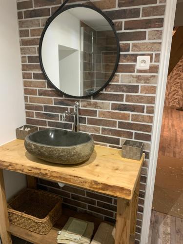 布里莱斯Chambre d’hôtes coconing的浴室的盥洗盆与砖墙上的镜子