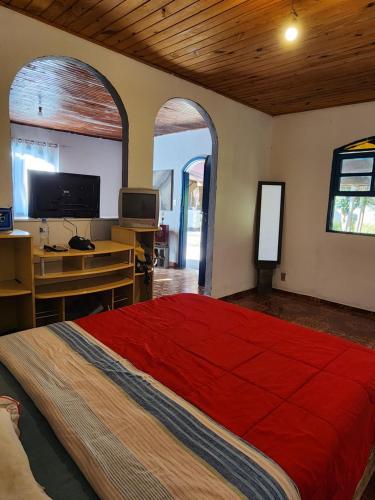 卢米亚Hospedaria e Camping Quintal do Mundo的一间卧室配有一张红色大床和一张书桌