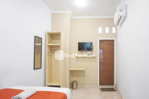 占碑市Tassa Homestay Syariah Mitra RedDoorz的一间卧室配有一张床,墙上配有电视