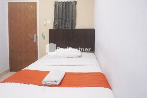 占碑市Tassa Homestay Syariah Mitra RedDoorz的一间卧室配有一张带白色床单和橙色毯子的床。
